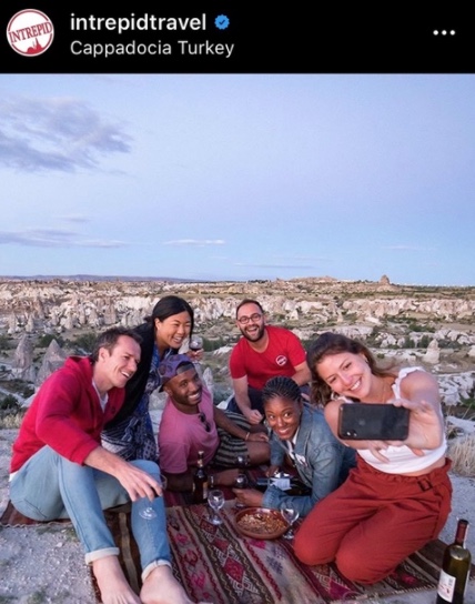 Auf dem Bild sind Reisende, die ein Selfie machen. Das Reiseunternehmen Intrepid Travel ist auf Social Media erfolgreich, denn es postet interessante Geschichten von Reisenden. So wird das Community-Gefühl gestärkt.