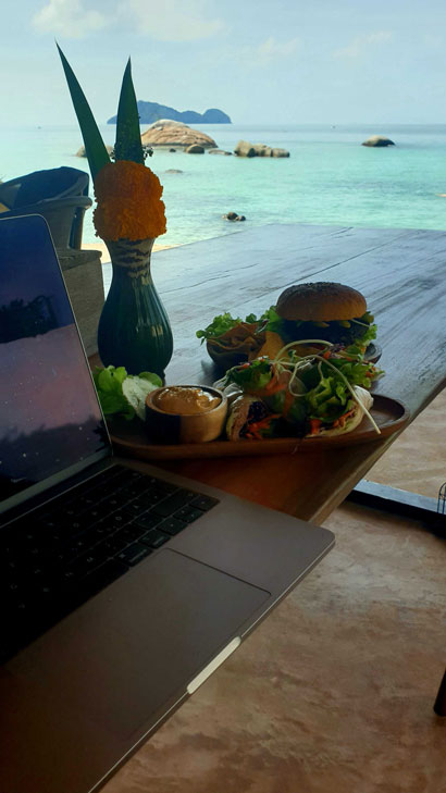 Foto vom Arbeiten mit Laptop in einem Strandcafé