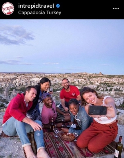 Auf dem Bild sind Reisende, die ein Selfie machen. Das Reiseunternehmen Intrepid Travel ist auf Social Media erfolgreich, denn es postet interessante Geschichten von Reisenden. So wird das Community-Gefühl gestärkt.